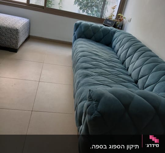 ספה מרופדת בצבע כחול בחדר עם חלון גדול